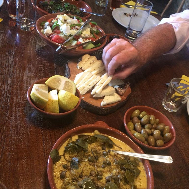 close-up of man eating cheese, olives, boiled plants, salad from ceramic bowls at 'Narlis Farm'